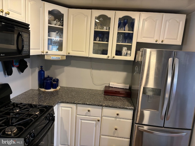 kitchen with dark stone counters, black appliances, and white cabinetry