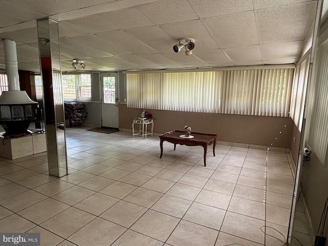 interior space with ceiling fan, a paneled ceiling, and light tile patterned floors