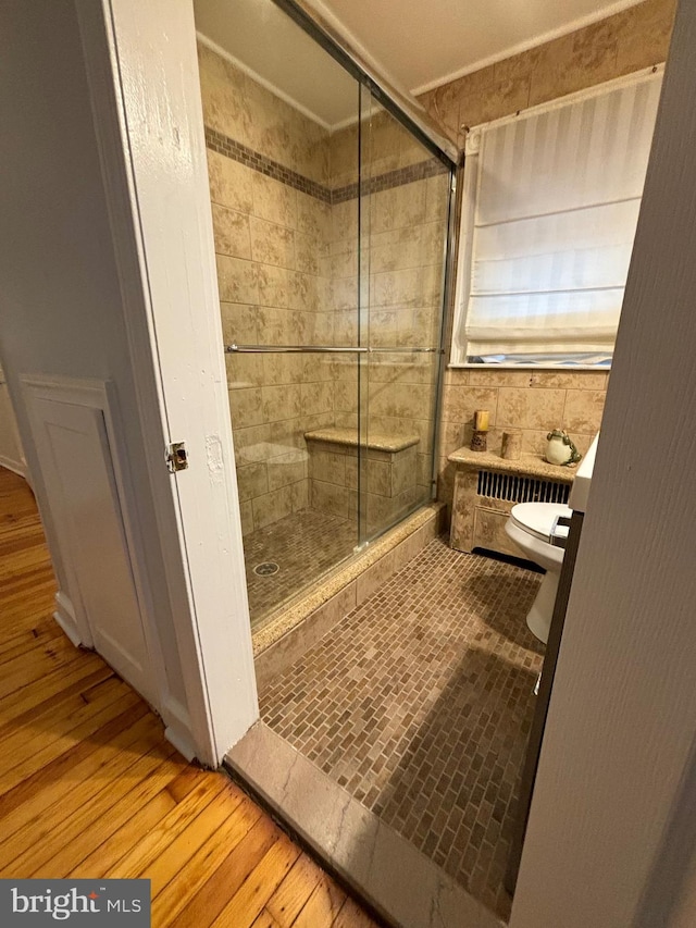 bathroom featuring tile walls, a shower with door, toilet, and hardwood / wood-style flooring