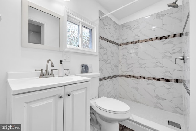 bathroom featuring a tile shower, vanity, and toilet