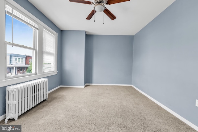 carpeted empty room featuring radiator heating unit and ceiling fan