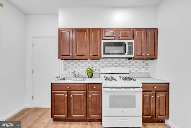 kitchen featuring sink, light wood-type flooring, gas range gas stove, and tasteful backsplash