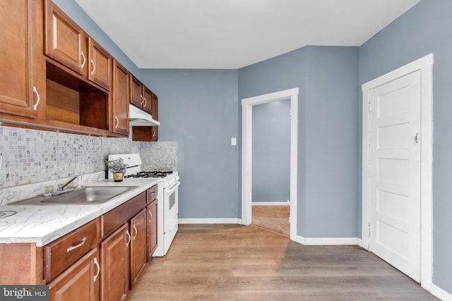 kitchen featuring light hardwood / wood-style floors, white gas stove, tasteful backsplash, and sink