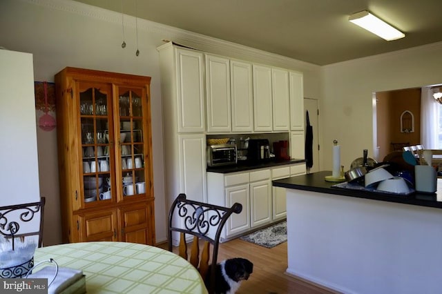 kitchen featuring white cabinets, light wood-type flooring, and crown molding