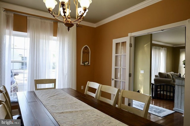 dining space with an inviting chandelier, ornamental molding, and dark hardwood / wood-style flooring