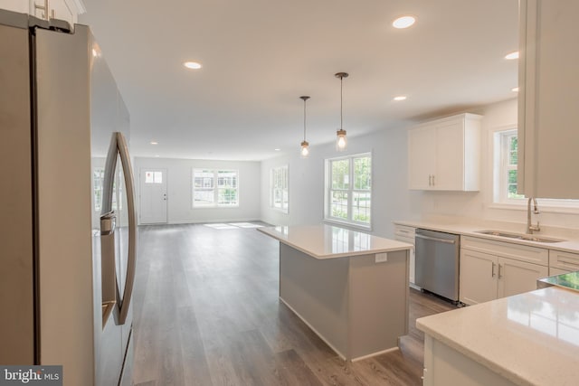 kitchen featuring appliances with stainless steel finishes, a kitchen island, a healthy amount of sunlight, and white cabinetry