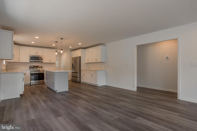 kitchen with a kitchen island, dark wood-type flooring, hanging light fixtures, appliances with stainless steel finishes, and white cabinetry