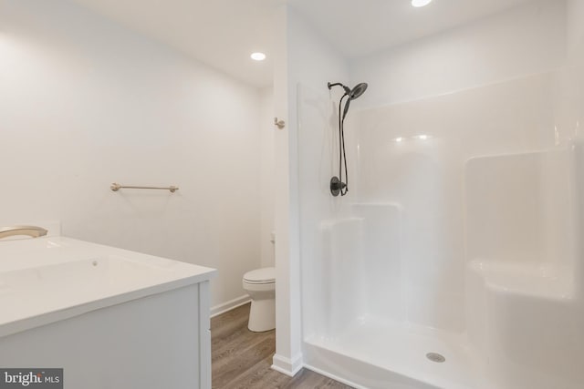 bathroom featuring wood-type flooring, vanity, toilet, and a shower