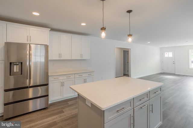 kitchen with light hardwood / wood-style floors, stainless steel fridge, pendant lighting, a kitchen island, and white cabinetry