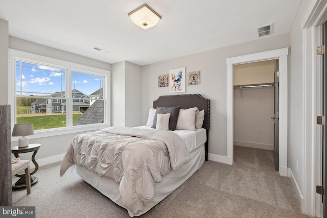 carpeted bedroom featuring a walk in closet and a closet