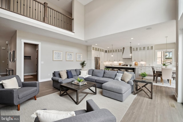 living room featuring a towering ceiling and light hardwood / wood-style floors