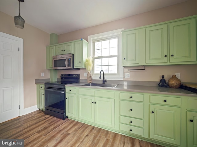 kitchen featuring light wood-type flooring, hanging light fixtures, black / electric stove, and sink