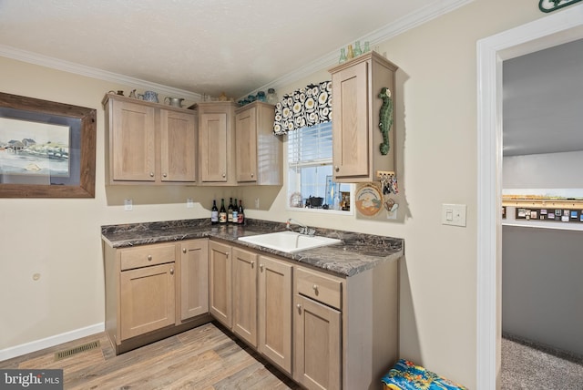 kitchen featuring light wood-type flooring, ornamental molding, sink, and light brown cabinets