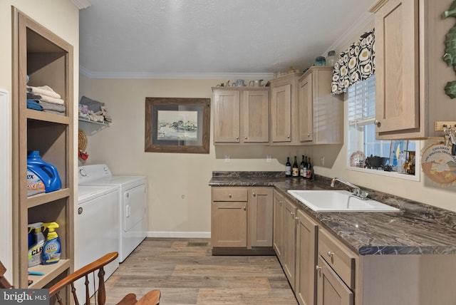 clothes washing area with sink, washer and clothes dryer, cabinets, light wood-type flooring, and crown molding