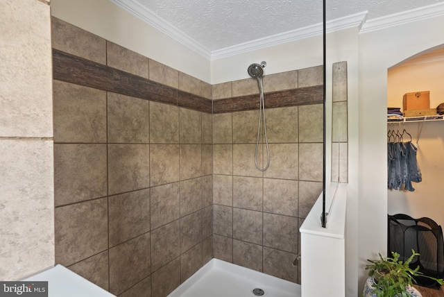 bathroom featuring a textured ceiling, tiled shower, and ornamental molding