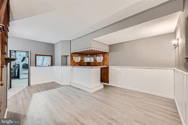 spare room featuring washer / clothes dryer, light hardwood / wood-style flooring, and wood walls