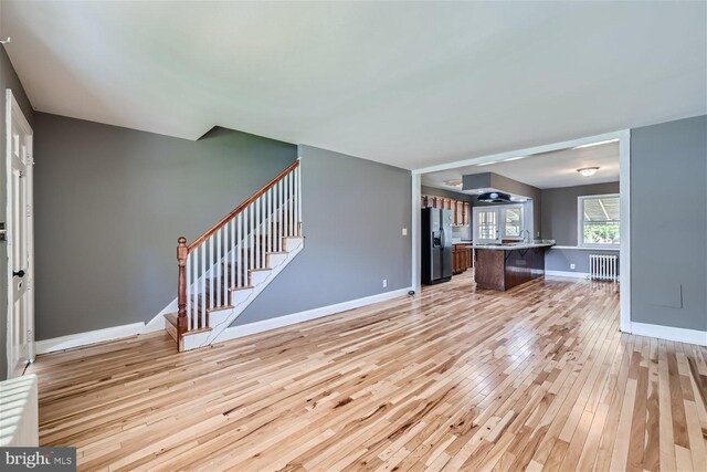 unfurnished living room with light wood-type flooring and radiator heating unit