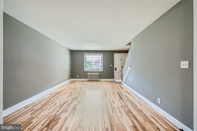 unfurnished living room featuring radiator and light hardwood / wood-style floors