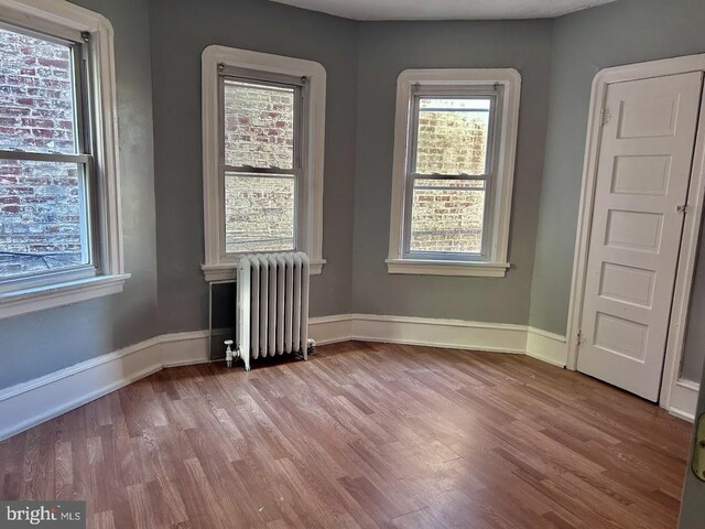 1128 Everett St, Camden, NJ 08104 - unfurnished room featuring radiator, a healthy amount of sunlight, and wood finished floors