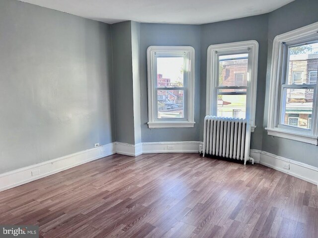 1128 Everett St, Camden, NJ 08104 - empty room with baseboards, radiator heating unit, and wood finished floors