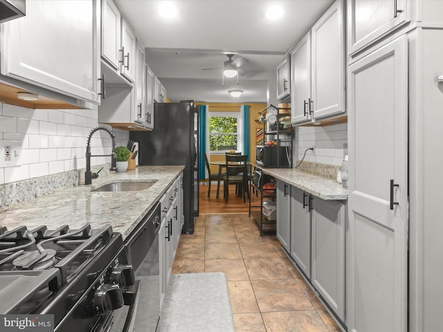 kitchen with appliances with stainless steel finishes, sink, backsplash, ceiling fan, and light stone counters