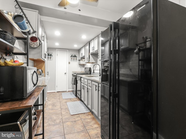 kitchen featuring stainless steel appliances, sink, light stone counters, and light tile patterned floors