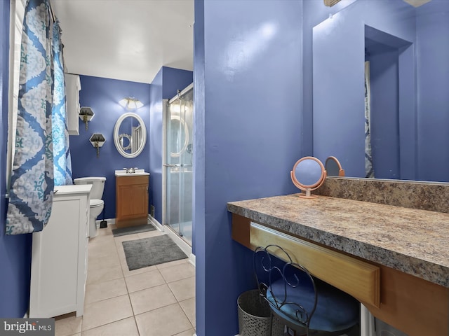 bathroom featuring toilet, walk in shower, vanity, and tile patterned floors