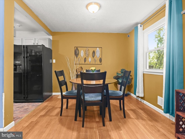 dining space featuring a textured ceiling and light hardwood / wood-style floors