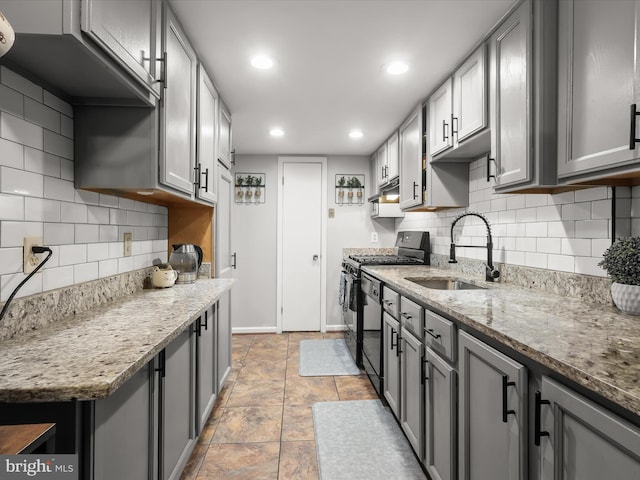 kitchen featuring backsplash, sink, gray cabinets, light stone counters, and gas stove