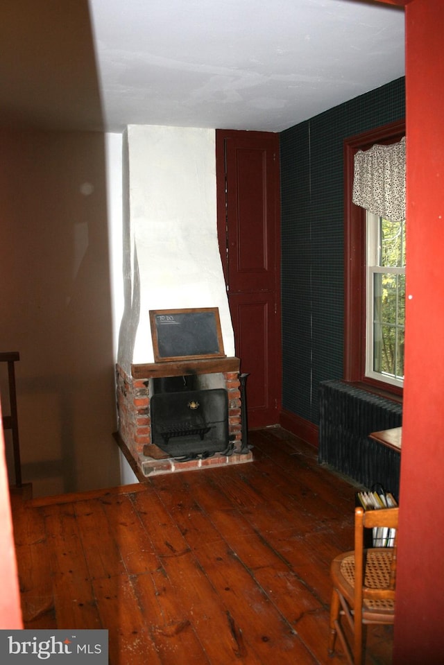 unfurnished living room featuring dark wood-type flooring and radiator heating unit