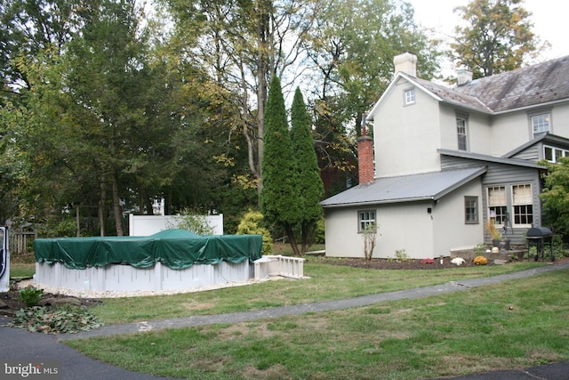 view of property exterior featuring a yard and a covered pool