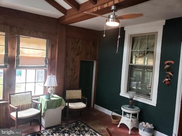 living area with ceiling fan, beam ceiling, and concrete flooring