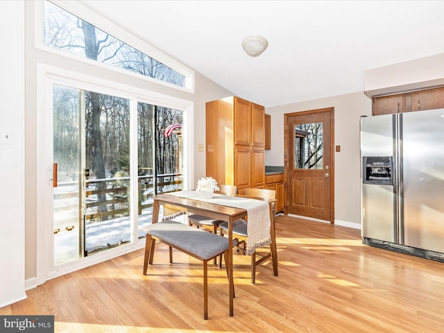 dining room with vaulted ceiling, plenty of natural light, and light wood-type flooring