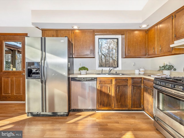 kitchen with stainless steel appliances, a healthy amount of sunlight, sink, and light wood-type flooring