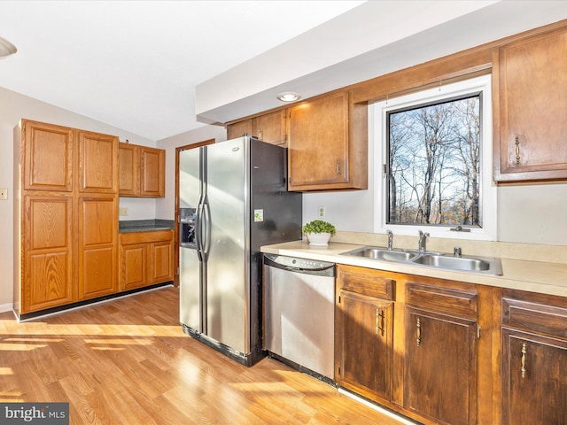 kitchen featuring vaulted ceiling, appliances with stainless steel finishes, sink, and light wood-type flooring