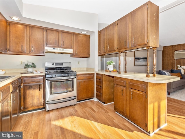 kitchen featuring sink, gas range, light wood-type flooring, kitchen peninsula, and a wall unit AC