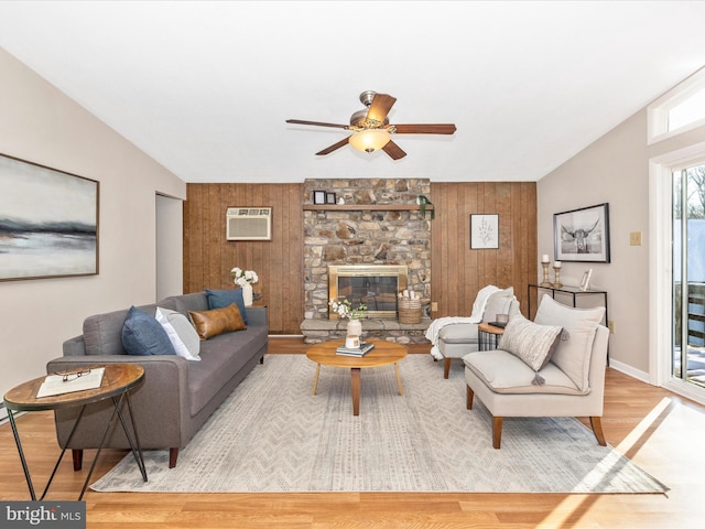 living room featuring light hardwood / wood-style flooring, a fireplace, wooden walls, and lofted ceiling