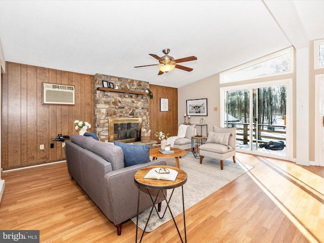 living room featuring a stone fireplace, hardwood / wood-style floors, wooden walls, lofted ceiling, and a wall mounted AC