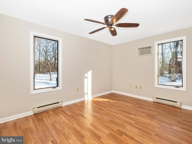 empty room featuring baseboard heating, a wealth of natural light, and light wood-type flooring