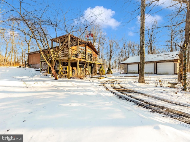 view of front facade featuring a wooden deck, a garage, and an outdoor structure