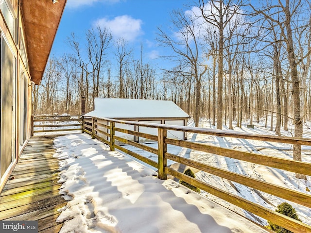 snow covered deck with a garage and an outbuilding