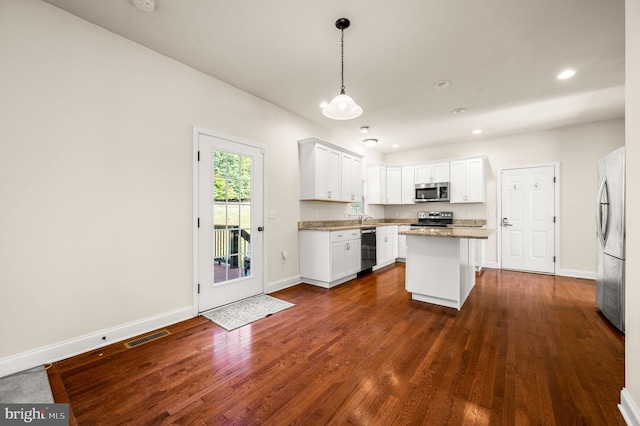 kitchen with dark wood-type flooring, white cabinets, hanging light fixtures, a kitchen island, and stainless steel appliances