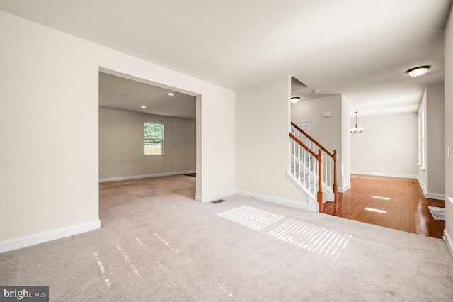 empty room featuring a notable chandelier and light hardwood / wood-style flooring