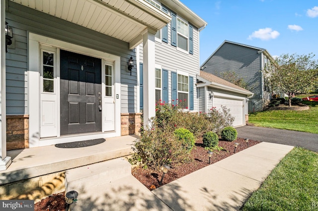 property entrance featuring a yard, a garage, and covered porch