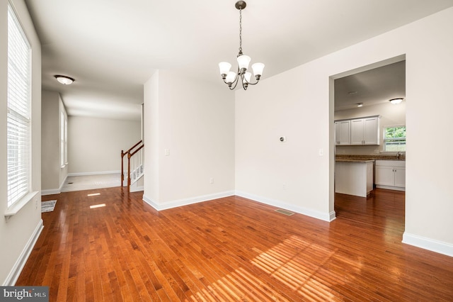 unfurnished room with wood-type flooring and a notable chandelier