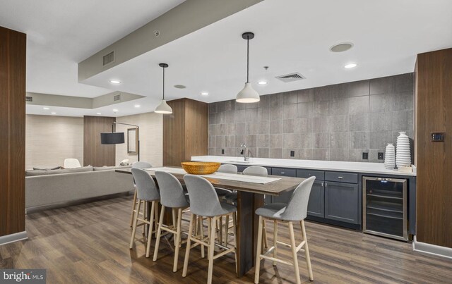 kitchen with wine cooler, a kitchen island, dark hardwood / wood-style flooring, tile walls, and decorative light fixtures