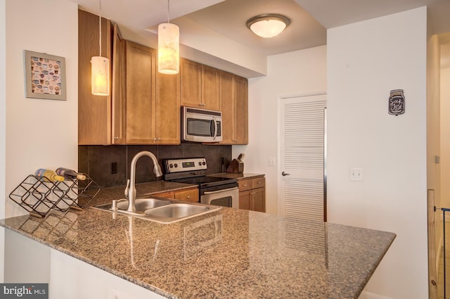 kitchen featuring kitchen peninsula, stainless steel appliances, hanging light fixtures, and sink