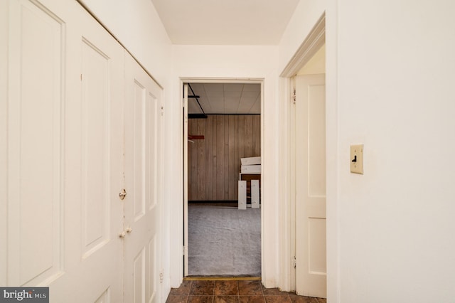 hallway with wooden walls and dark colored carpet