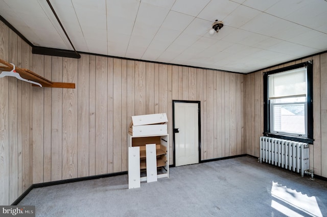 carpeted spare room with radiator heating unit and wooden walls