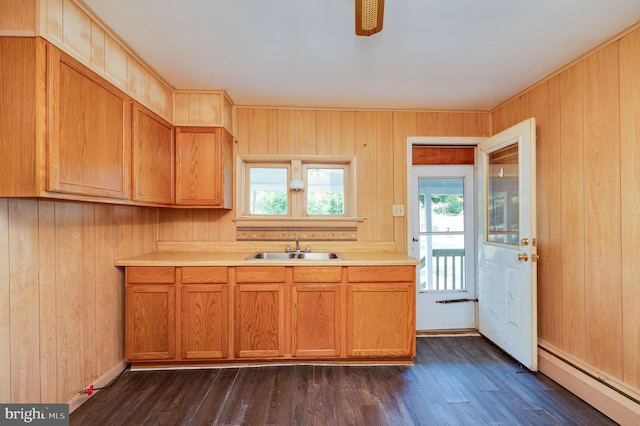 kitchen featuring dark hardwood / wood-style floors, wooden walls, baseboard heating, and sink